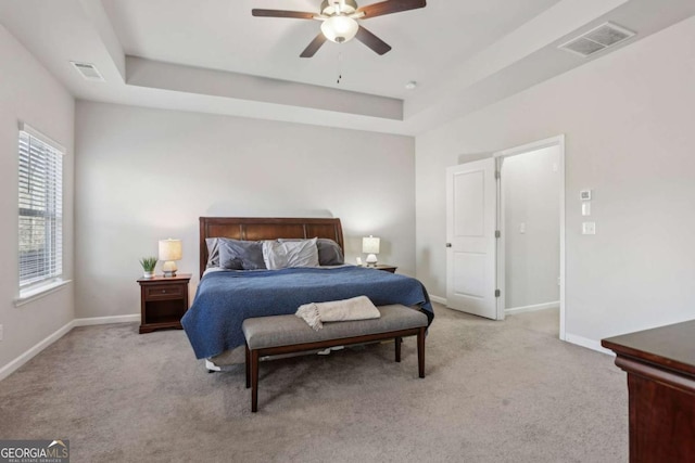 bedroom with a raised ceiling, light carpet, and ceiling fan