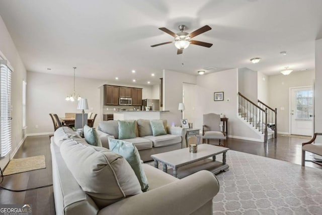 living room featuring ceiling fan with notable chandelier and dark wood-type flooring