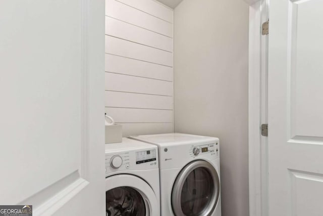 washroom featuring wooden walls and washer and clothes dryer