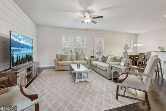 living room featuring a wealth of natural light, wood-type flooring, and ceiling fan with notable chandelier