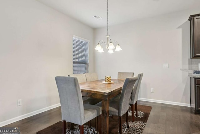 dining room with dark hardwood / wood-style flooring and a chandelier