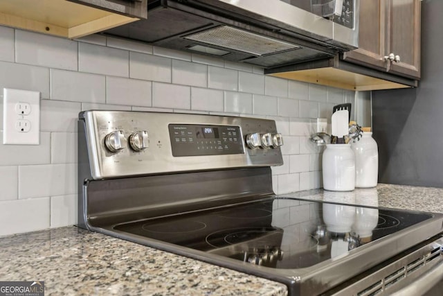 kitchen featuring stainless steel range with electric stovetop, light stone counters, and decorative backsplash