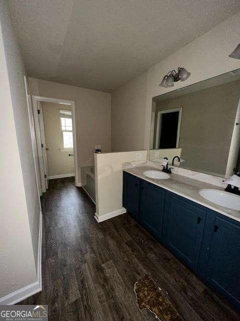 bathroom with vanity, hardwood / wood-style floors, a bathtub, and a textured ceiling