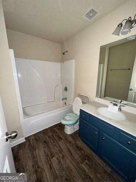 full bathroom featuring shower / tub combination, hardwood / wood-style flooring, vanity, toilet, and a textured ceiling