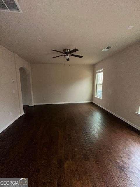 empty room featuring dark wood-type flooring, ceiling fan, and a textured ceiling