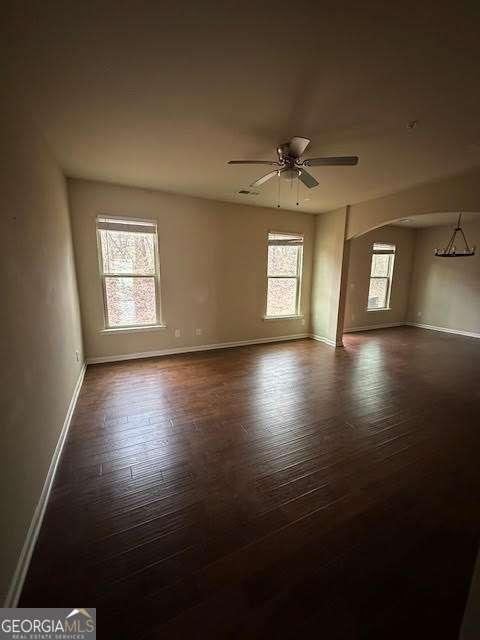 unfurnished room featuring dark wood-type flooring and ceiling fan