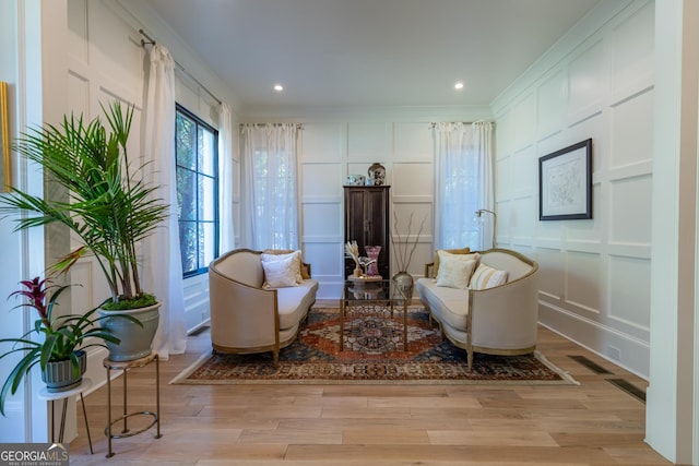 living area with crown molding and light wood-type flooring