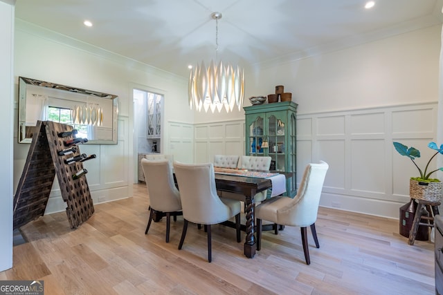 dining area featuring crown molding, light wood-type flooring, and an inviting chandelier