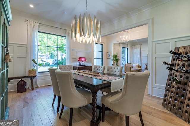 dining space featuring an inviting chandelier, ornamental molding, and light hardwood / wood-style floors