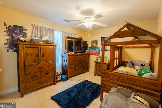 carpeted bedroom featuring ceiling fan and a textured ceiling