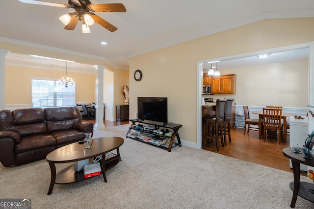 carpeted living room with ornate columns, ornamental molding, and ceiling fan with notable chandelier