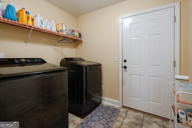 clothes washing area featuring washing machine and clothes dryer, a textured ceiling, and light tile patterned floors