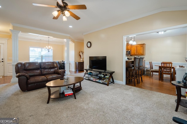 living room with crown molding, ceiling fan with notable chandelier, decorative columns, and carpet