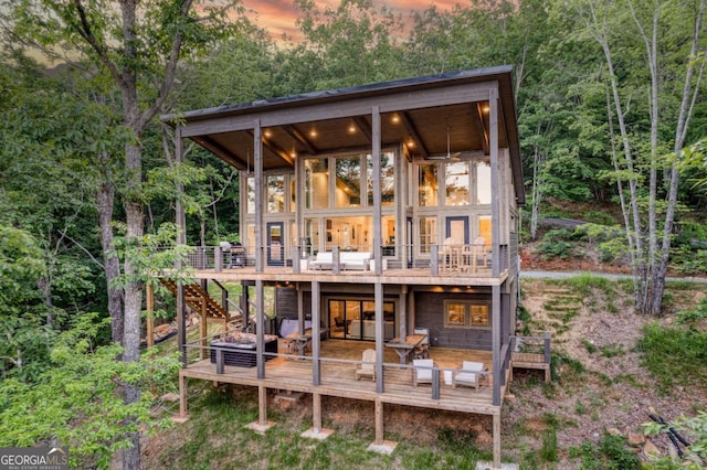 back house at dusk with a wooden deck