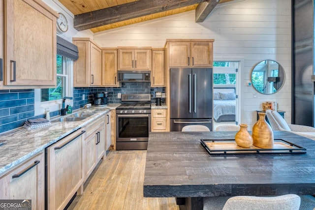 kitchen with lofted ceiling with beams, sink, decorative backsplash, light stone counters, and stainless steel appliances