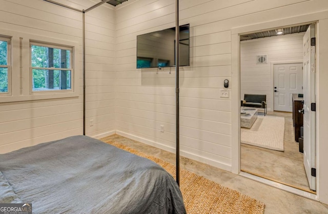 bedroom with wooden walls and concrete flooring