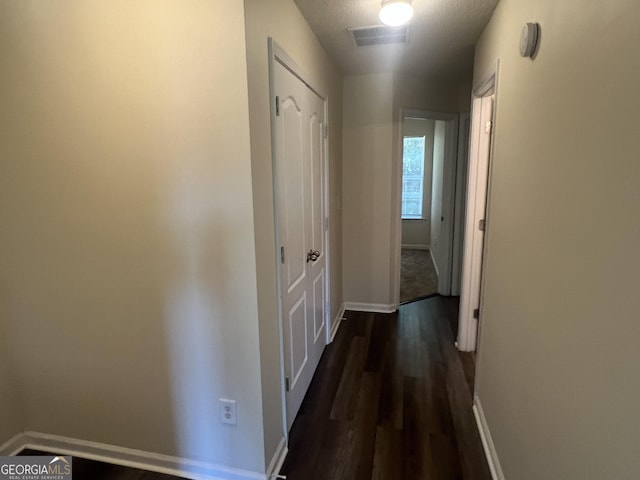 hallway with dark hardwood / wood-style floors and a textured ceiling