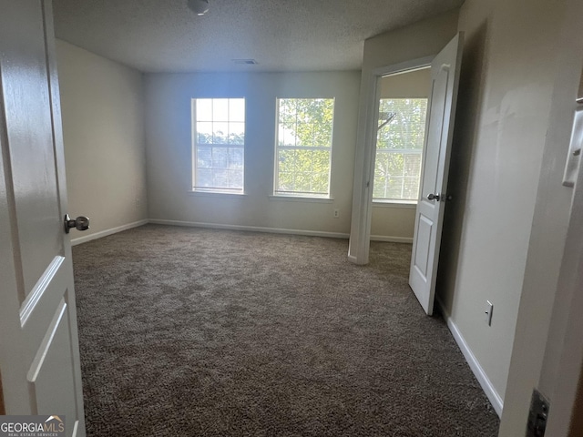 unfurnished room with carpet and a textured ceiling