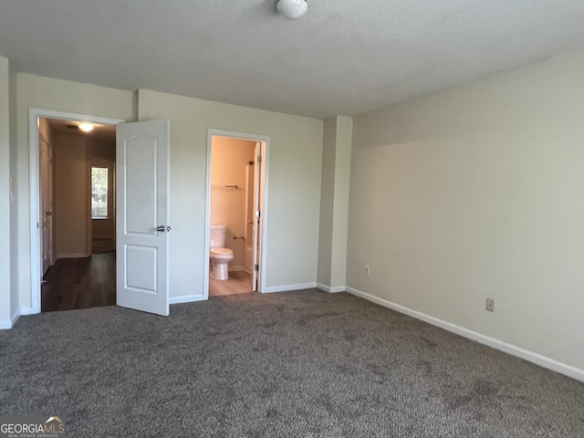 unfurnished bedroom with dark carpet and ensuite bath