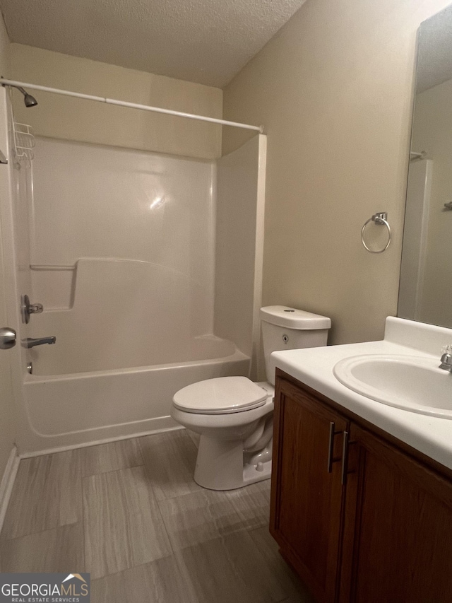 full bathroom featuring vanity, shower / washtub combination, a textured ceiling, and toilet