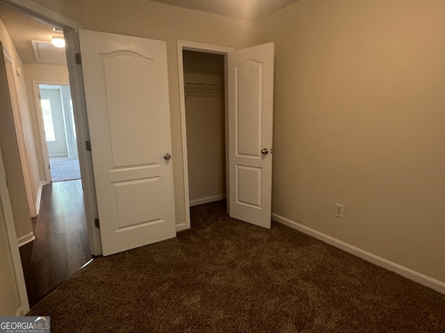 unfurnished bedroom featuring dark carpet and a closet