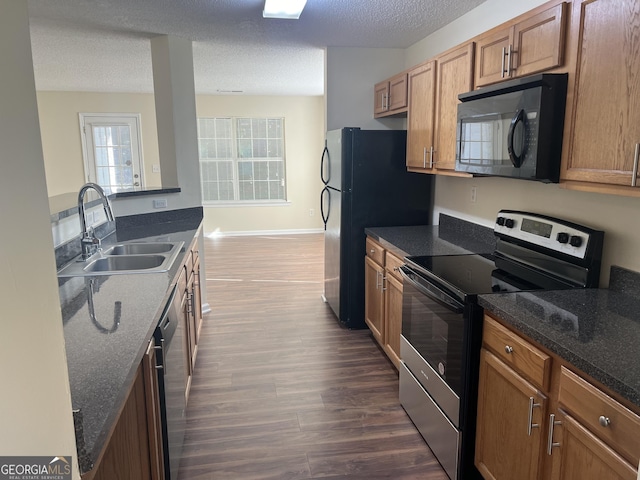 kitchen with sink, dark wood-type flooring, a textured ceiling, and black appliances