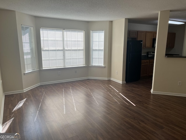 unfurnished living room with dark wood-type flooring and a textured ceiling