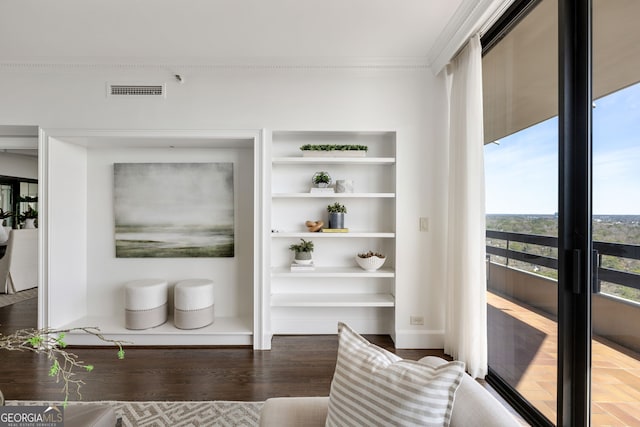 living area with built in shelves, visible vents, crown molding, and wood finished floors