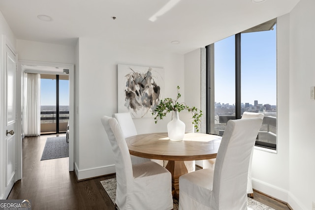 dining area with plenty of natural light, floor to ceiling windows, baseboards, and dark wood finished floors