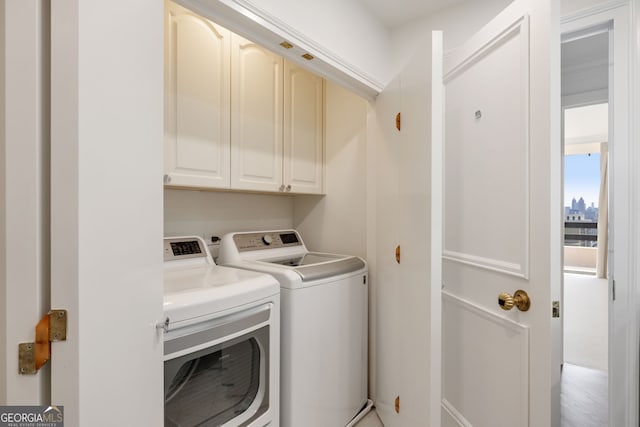 clothes washing area featuring cabinet space and separate washer and dryer