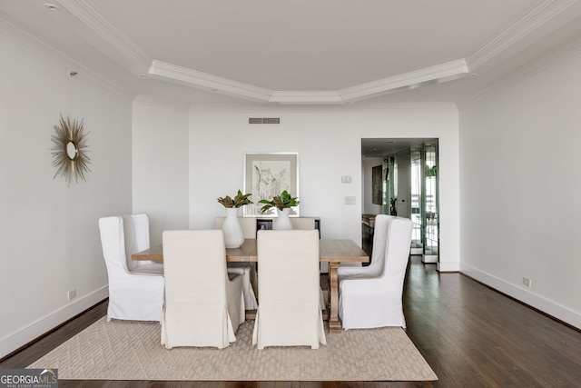 dining room featuring a tray ceiling, visible vents, ornamental molding, wood finished floors, and baseboards