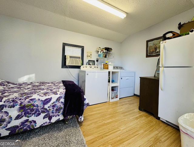 bedroom featuring washing machine and clothes dryer, lofted ceiling, light wood-type flooring, white refrigerator, and cooling unit