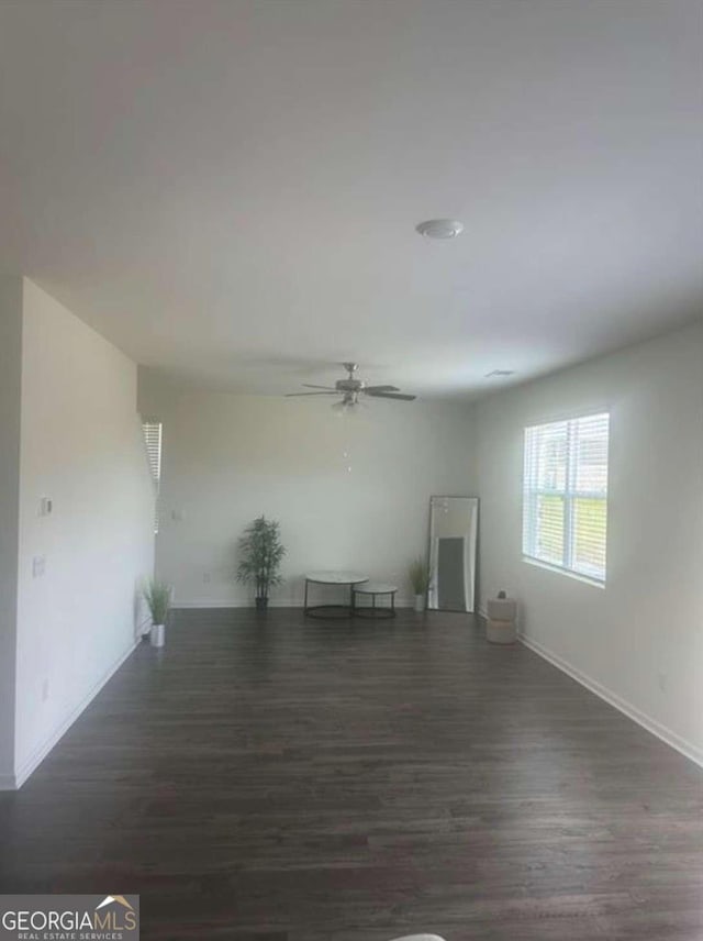 unfurnished room featuring dark wood-type flooring and ceiling fan