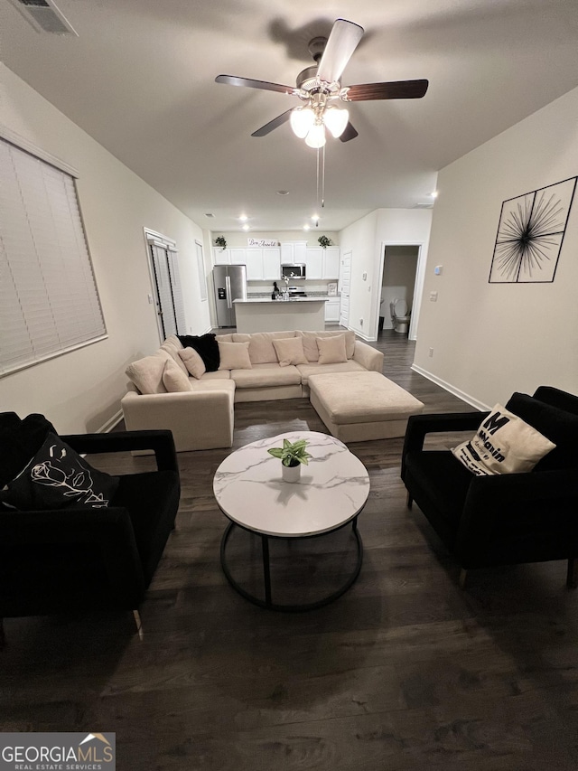 living room featuring ceiling fan and dark hardwood / wood-style floors