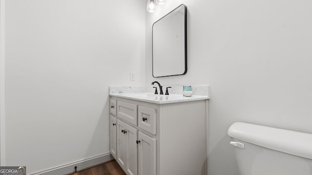 bathroom featuring vanity, wood-type flooring, and toilet