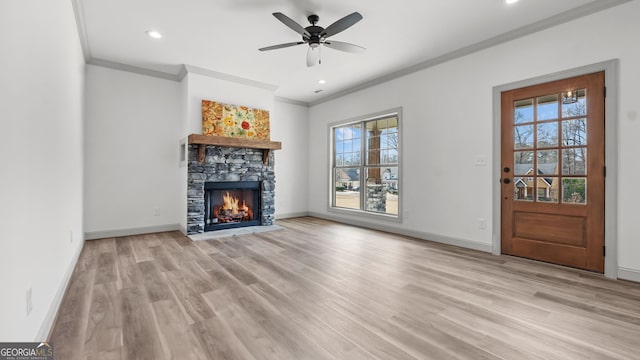 unfurnished living room featuring a stone fireplace, ornamental molding, ceiling fan, and light wood-type flooring