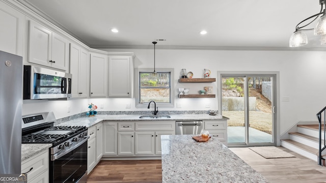 kitchen with appliances with stainless steel finishes, sink, hanging light fixtures, and white cabinets