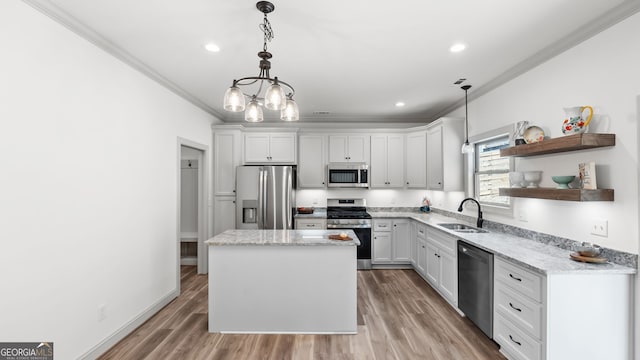 kitchen with pendant lighting, sink, white cabinetry, stainless steel appliances, and a center island