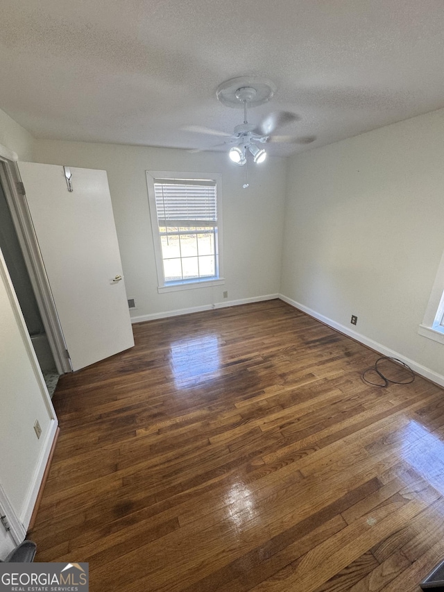 spare room with ceiling fan, dark wood-type flooring, and a textured ceiling