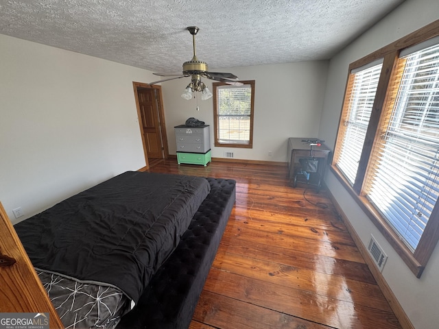 bedroom with hardwood / wood-style floors, a textured ceiling, and ceiling fan