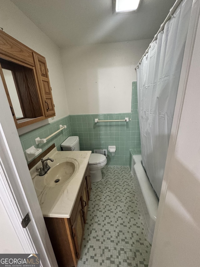 full bathroom with vanity, tile walls, toilet, and shower / bathtub combination with curtain