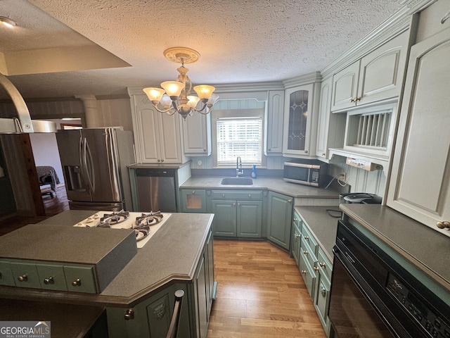 kitchen with sink, appliances with stainless steel finishes, decorative light fixtures, a chandelier, and light wood-type flooring