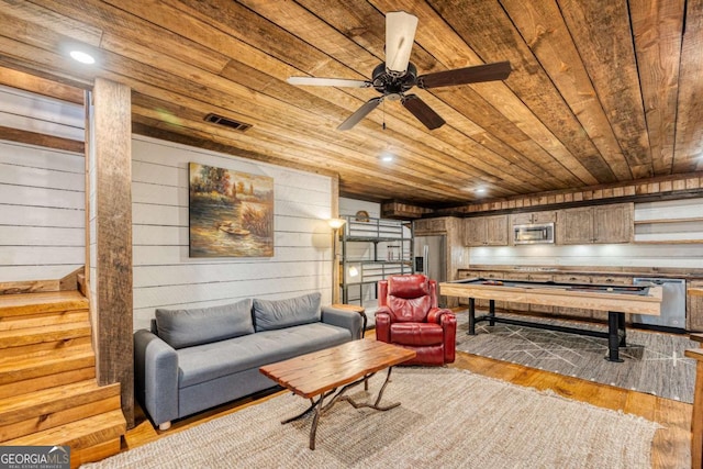 sitting room with ceiling fan, wood walls, wood ceiling, and light hardwood / wood-style flooring