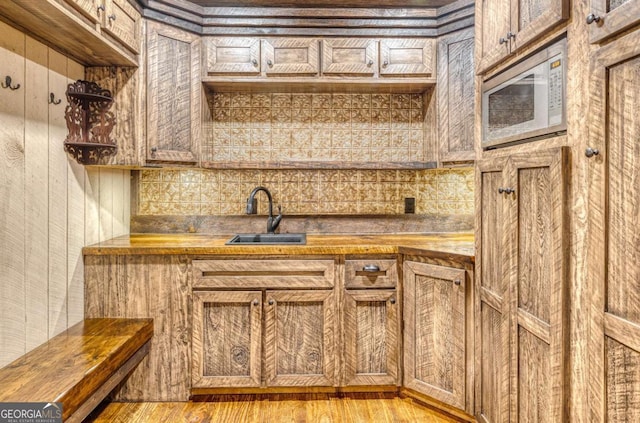 kitchen featuring sink, white microwave, wood counters, and light wood-type flooring