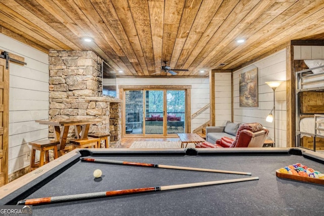 playroom with ceiling fan, wooden walls, pool table, wooden ceiling, and a barn door