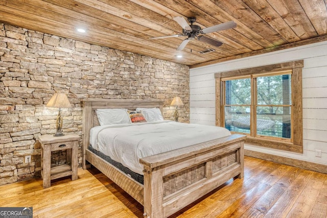 bedroom with wood walls, wood ceiling, and light hardwood / wood-style flooring