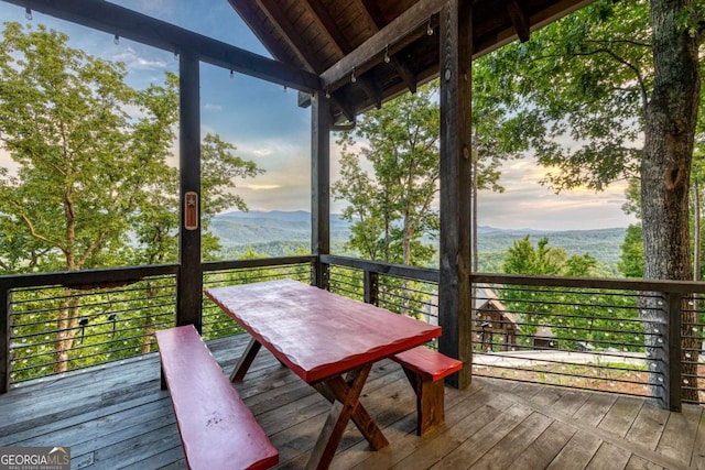 unfurnished sunroom featuring wood ceiling, a healthy amount of sunlight, a mountain view, and vaulted ceiling