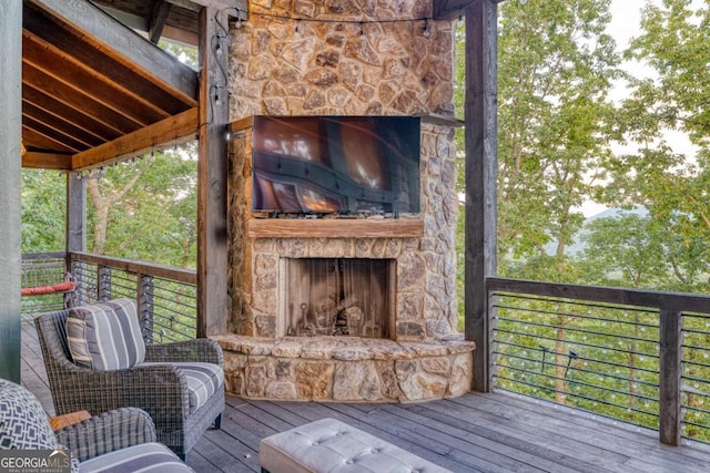 wooden terrace with an outdoor stone fireplace