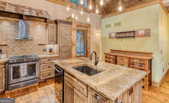 kitchen featuring wall chimney exhaust hood, stainless steel gas range, sink, a center island with sink, and black dishwasher