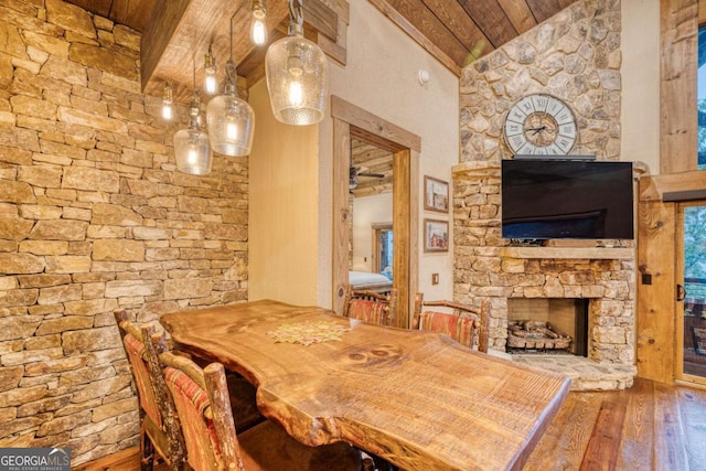 dining room featuring wood ceiling, hardwood / wood-style floors, beam ceiling, high vaulted ceiling, and a fireplace